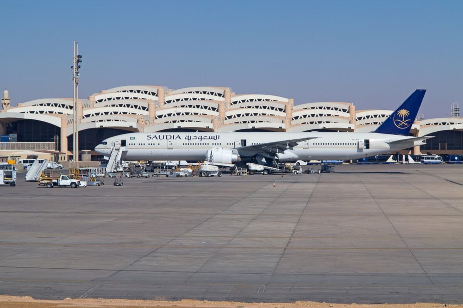 A Saudia passenger jet parked on the tarmac in front of the arched terminal of King Khalid International Airport in Riyadh.